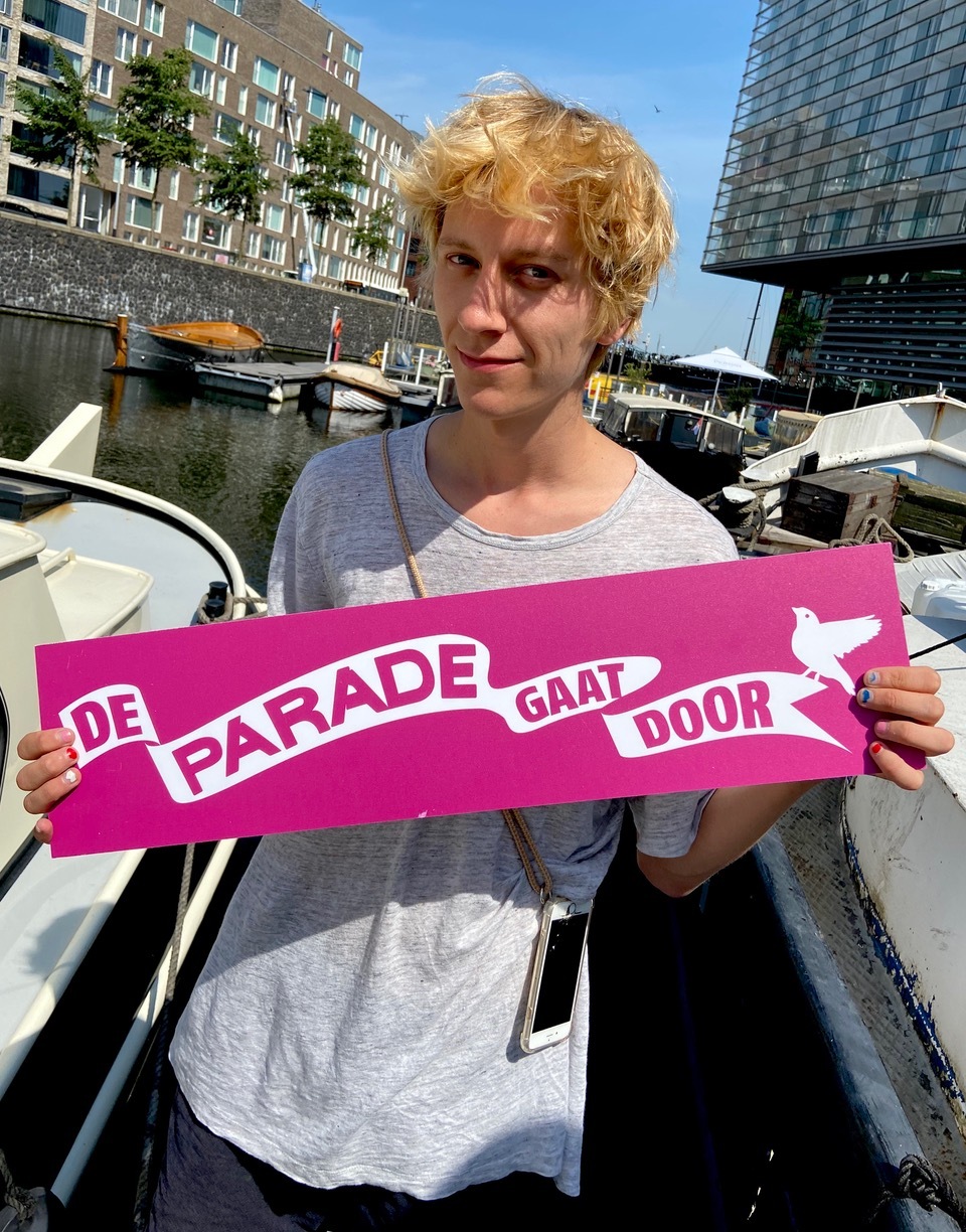 Man houdt roze bord met witte tekst 