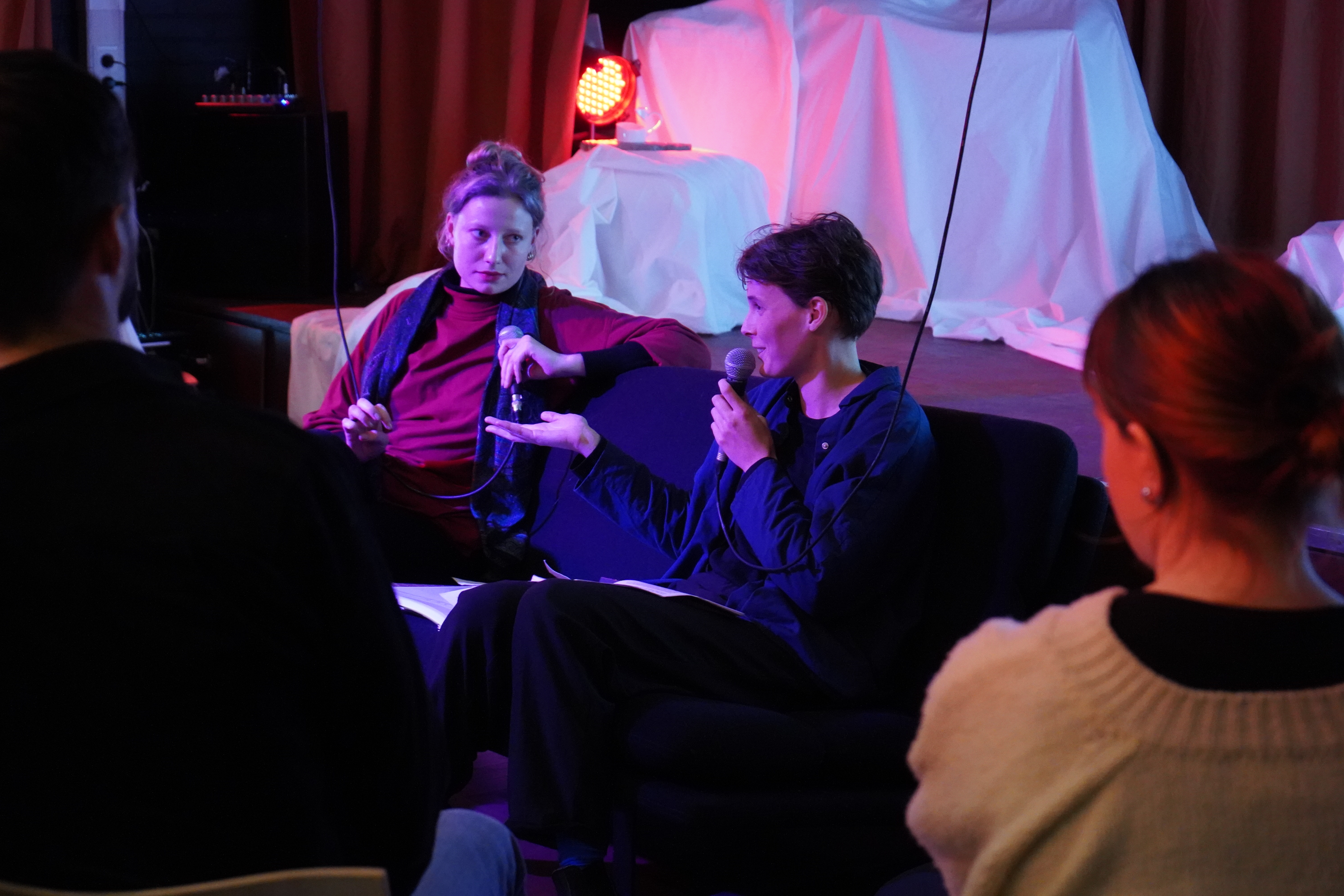 Twee personen zitten op een bank met een microfoon in hun hand