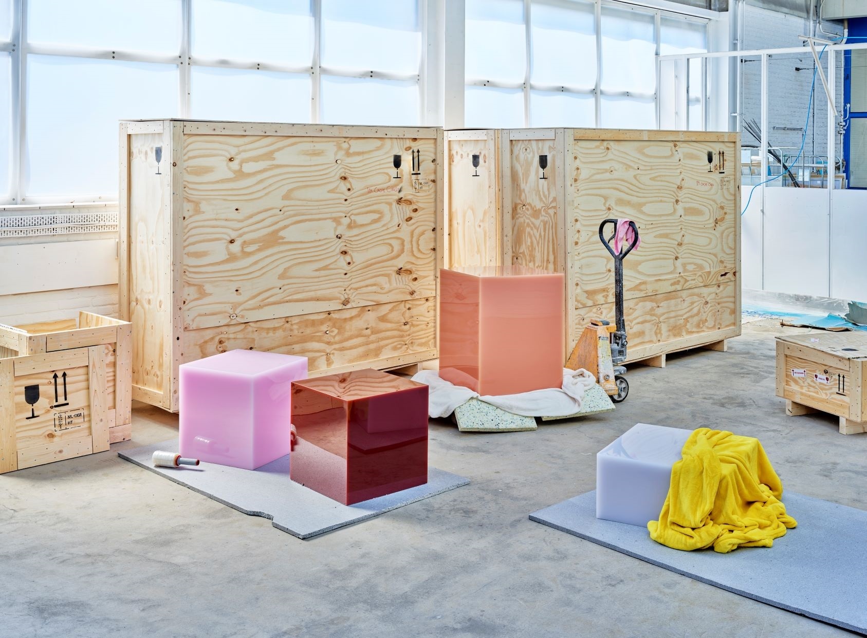 Gekleurde kubussen van kunsthars op de voorgrond, daarachter verhuiskisten.