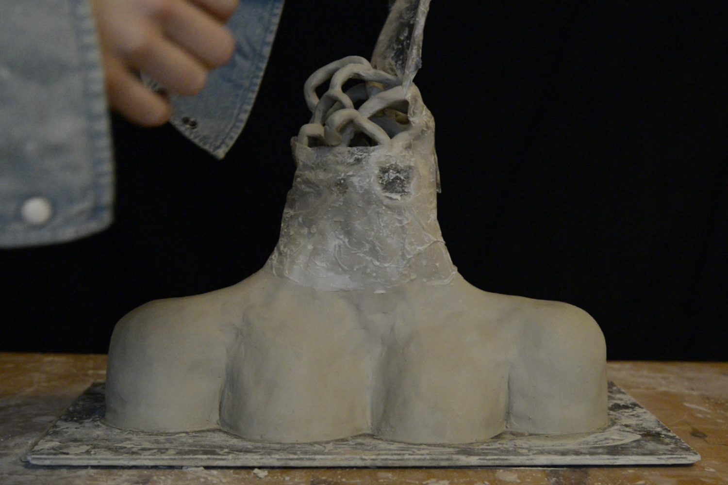 Een persoon maakt een beeldhouwwerk van klei.