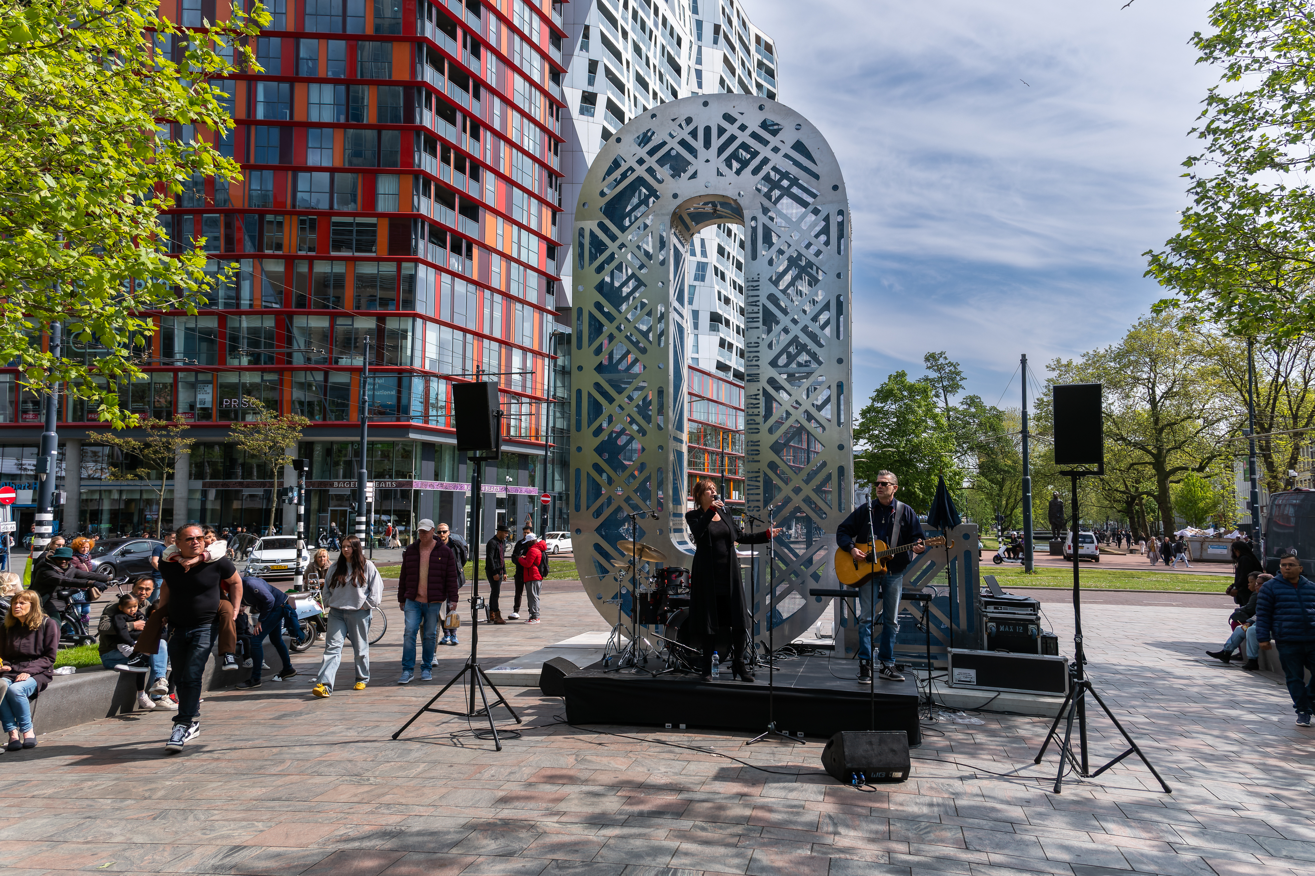 Optreden van zangeres met gitarist bij een kunstwerk / installatie in de vorm van de letter O.