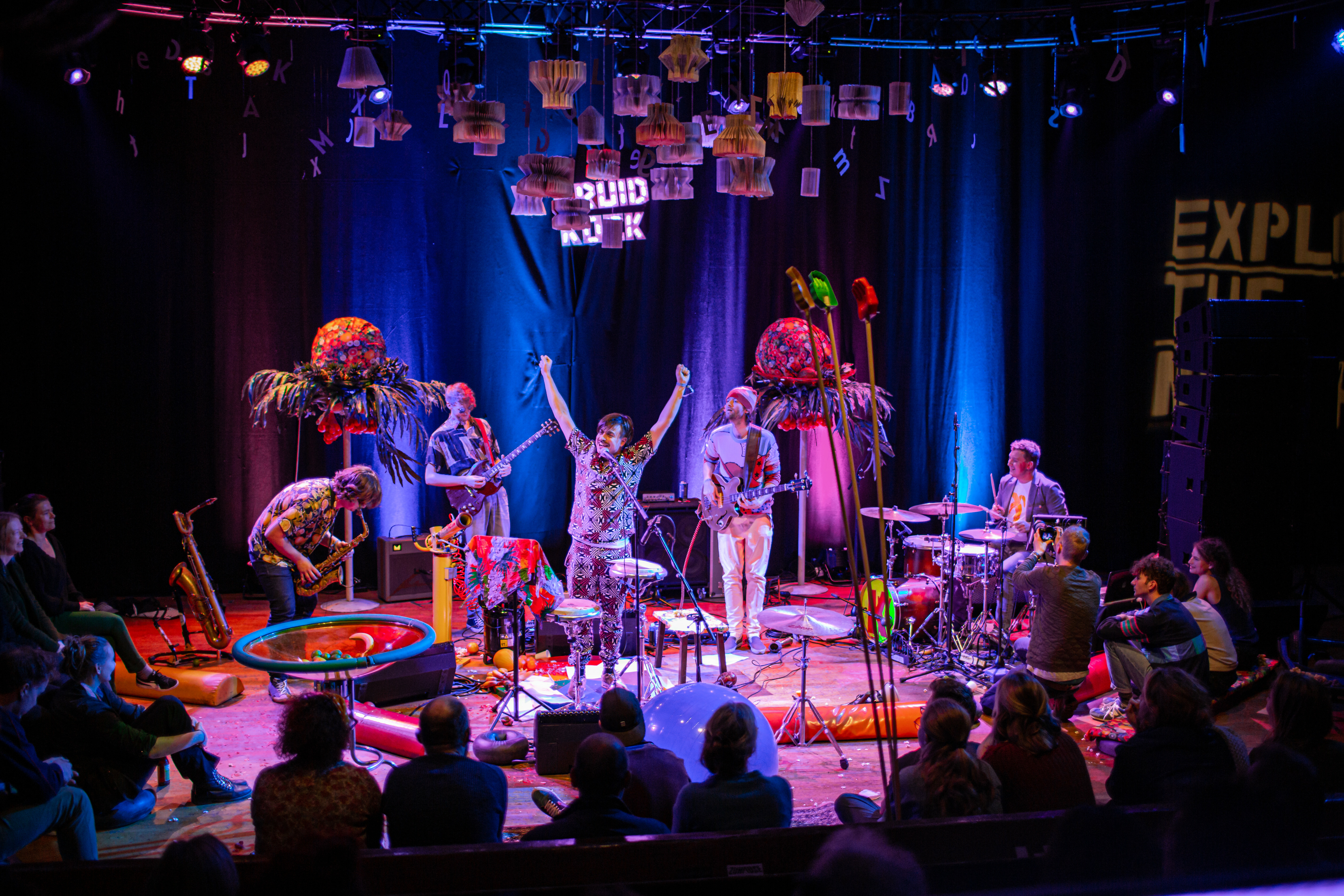 Schrijver, dichter en performer Joost Oomen met handen in de lucht tijdens een optreden samen met de vier leden van de garagejazzband Kruidkoek