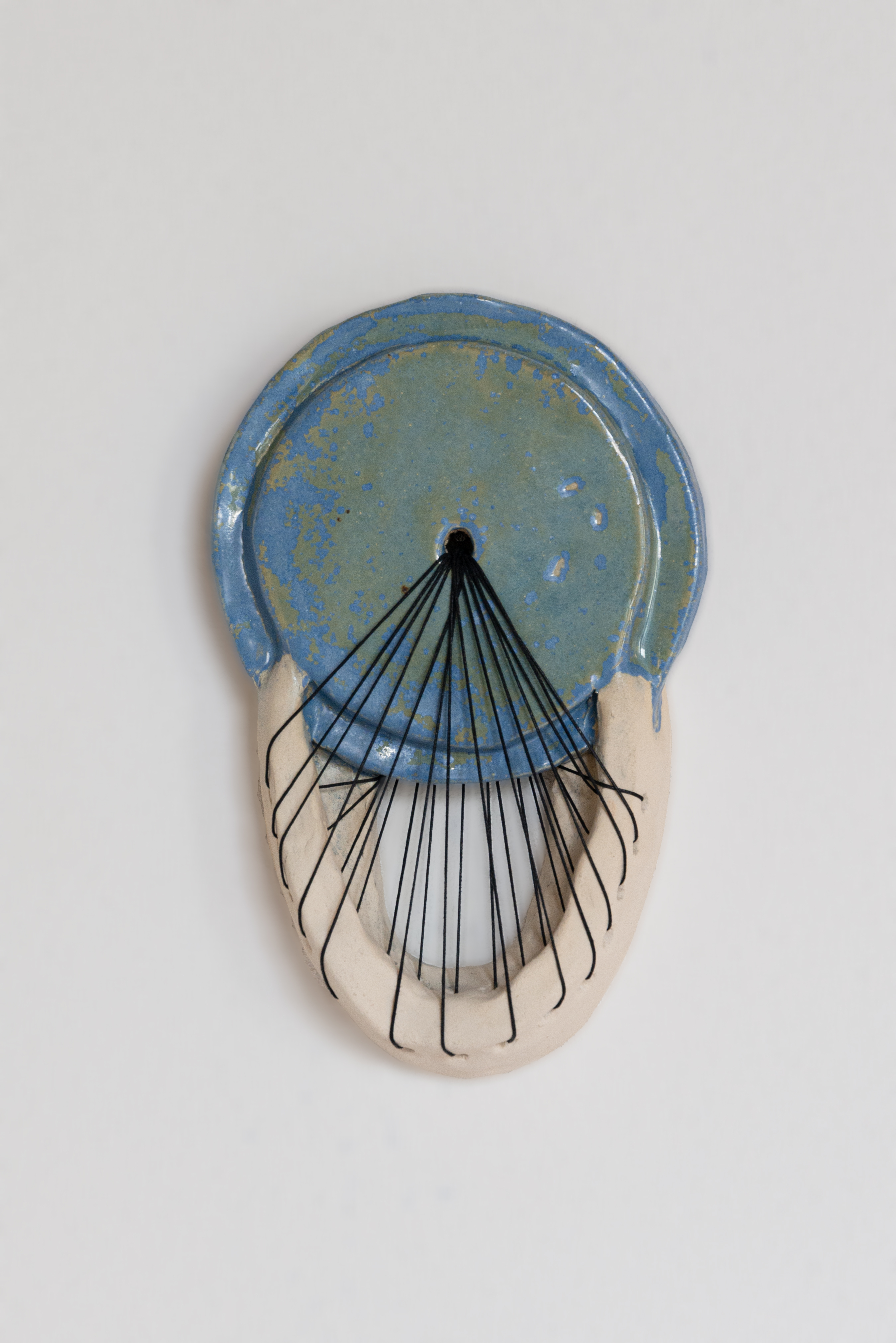 Een blauw-wit keramisch stuk met een draad. Gemaakt door Leonie Fernhout.