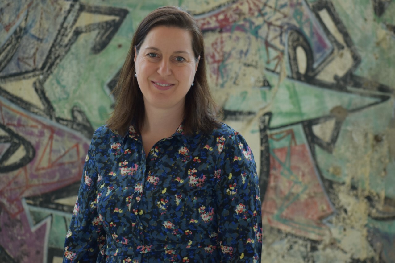 portretfoto van Nicolle van Lith, die staat voor een muur met graffitti