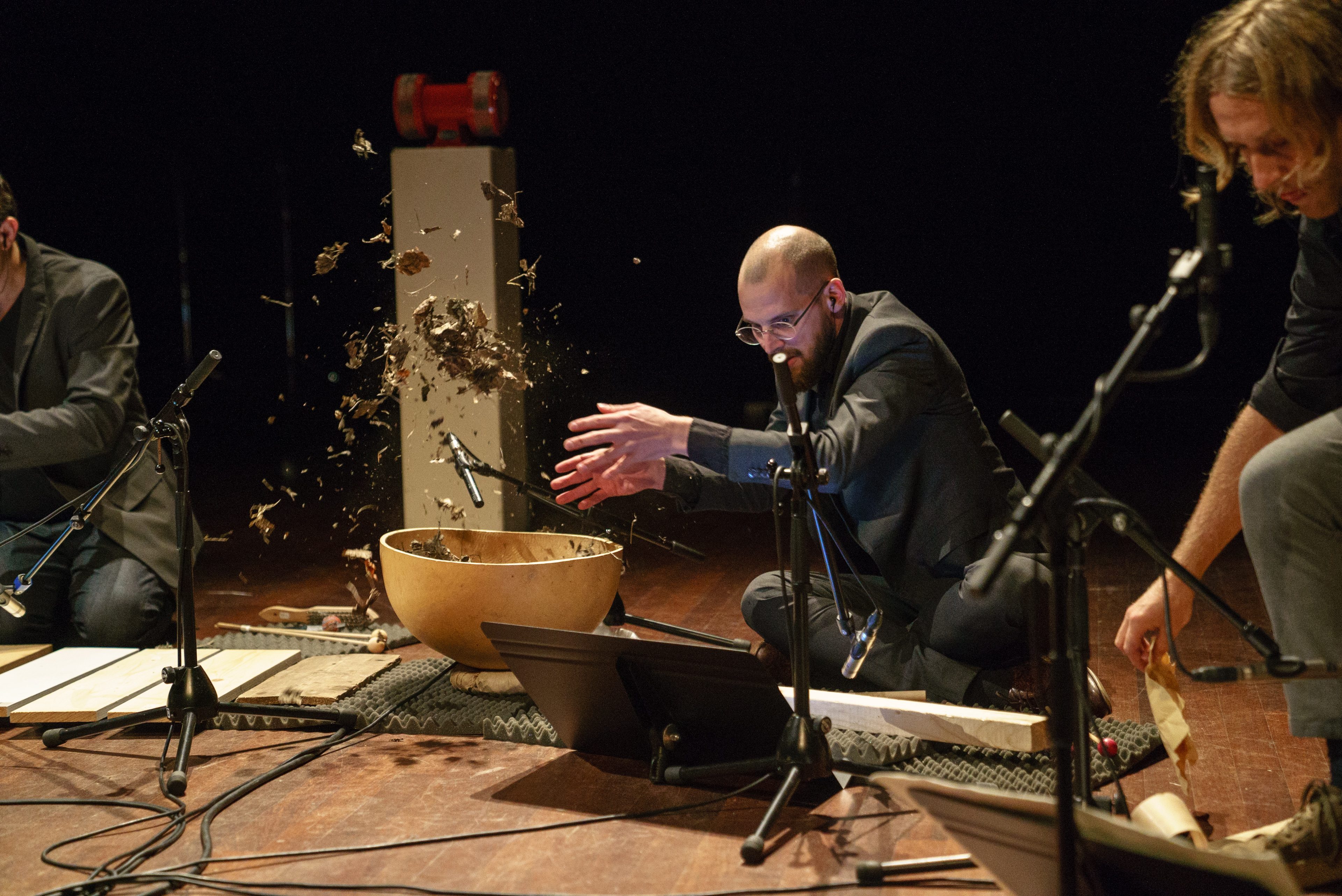 muziekgezelschap op het podium, man in midden die blaadjes opgooit